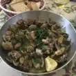 Poêle d'ameijoas à Bulhão Pato fumantes au centre d'une table familiale, avec pain rustique et vin blanc