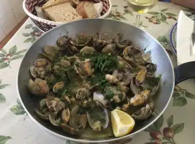Poêle d'ameijoas à Bulhão Pato fumantes au centre d'une table familiale, avec pain rustique et vin blanc