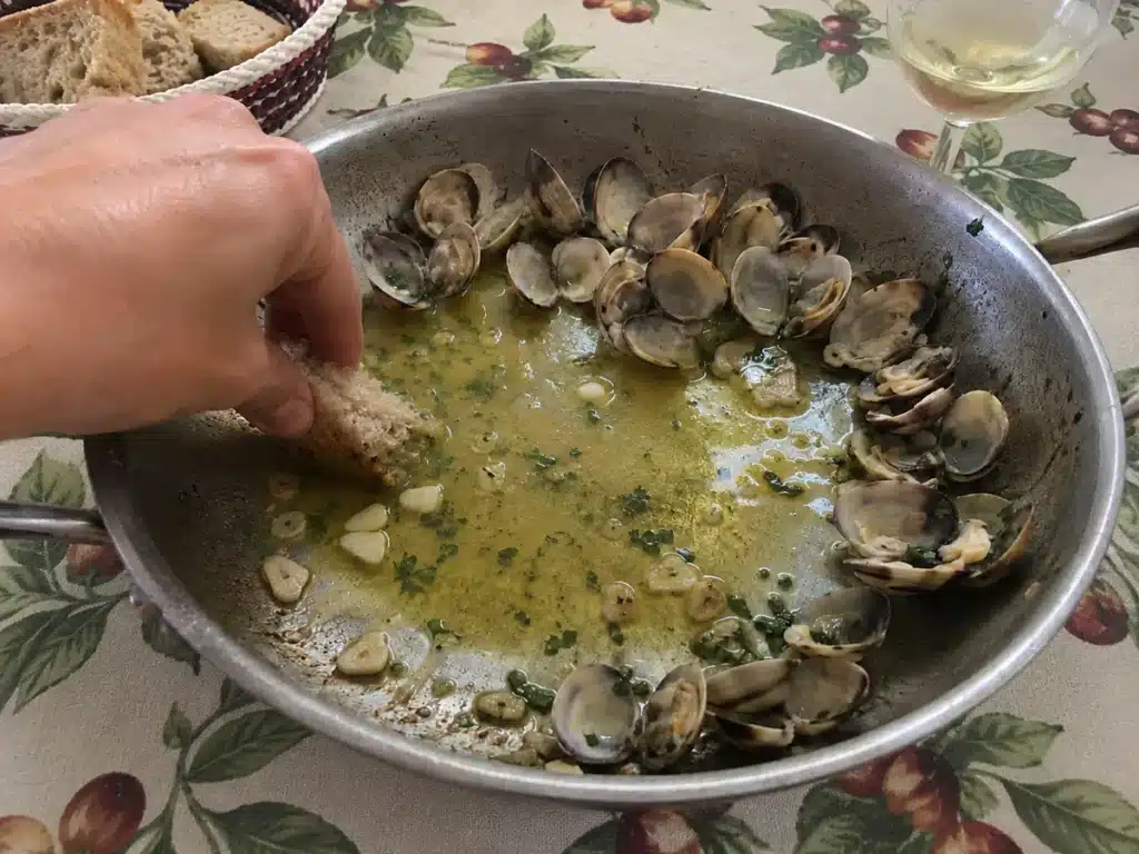 Morceau de pain de campagne trempé dans le molho des ameijoas à Bulhão Pato en fin de repas
